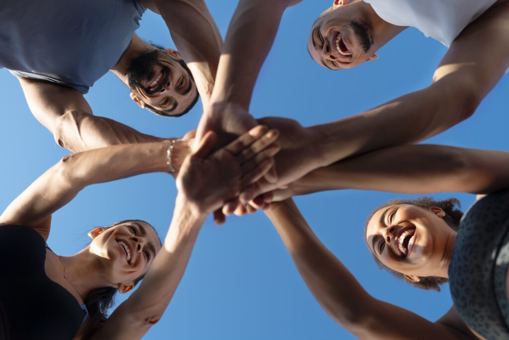 group-people-putting-their-hands-together-while-exercising-outdoors